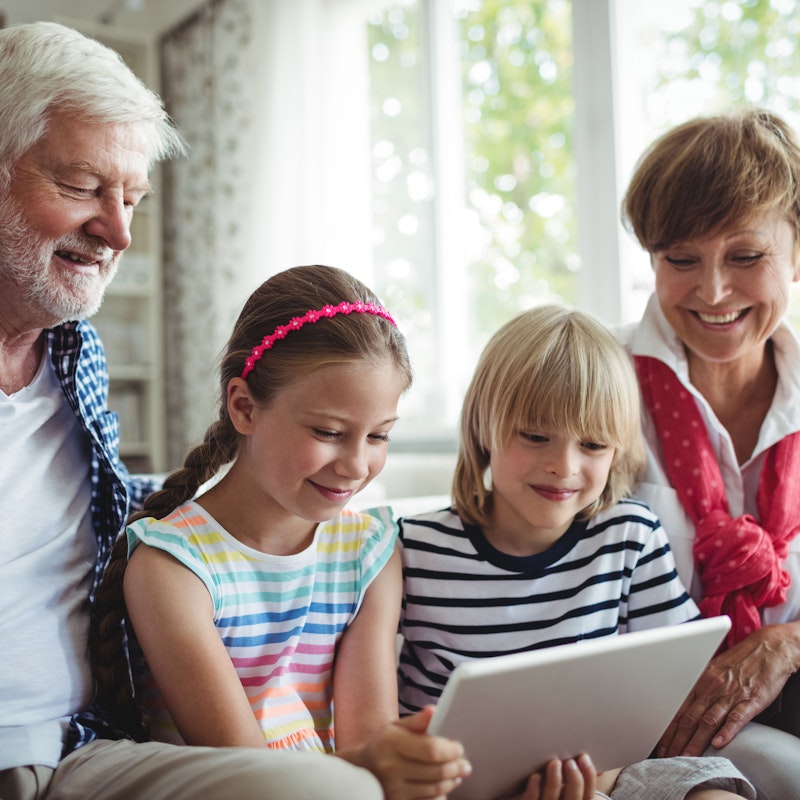 Äldre par tittar på en surfplatta tillsammans med barnbarnen